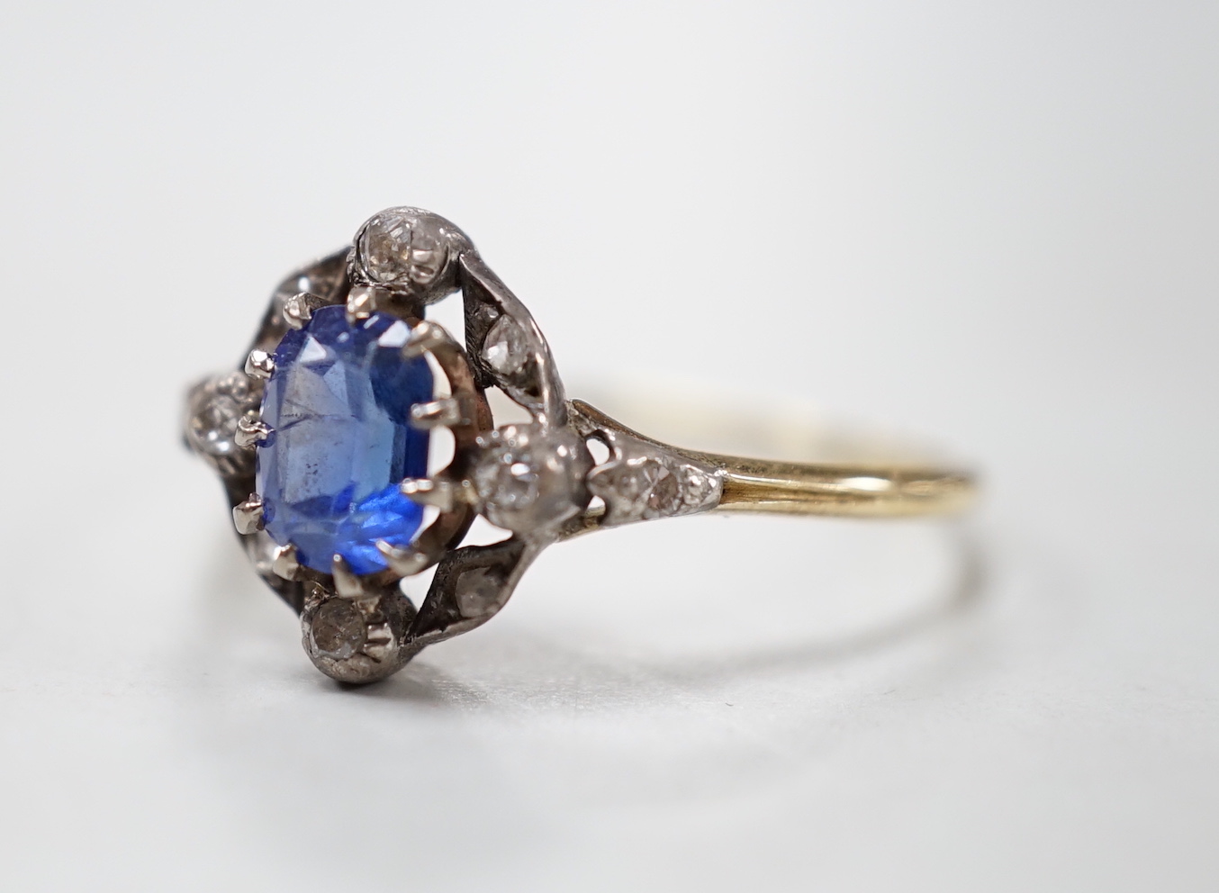 An early 20th century yellow metal, sapphire and diamond cluster set oval cluster ring, size R/S, gross weight 2.1 grams.